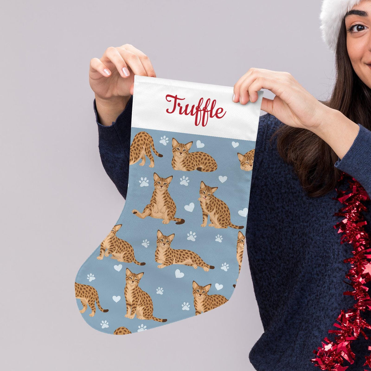Ocicat Christmas stocking on dusty blue background with example name Truffle in red script on the white cuff; view 5.