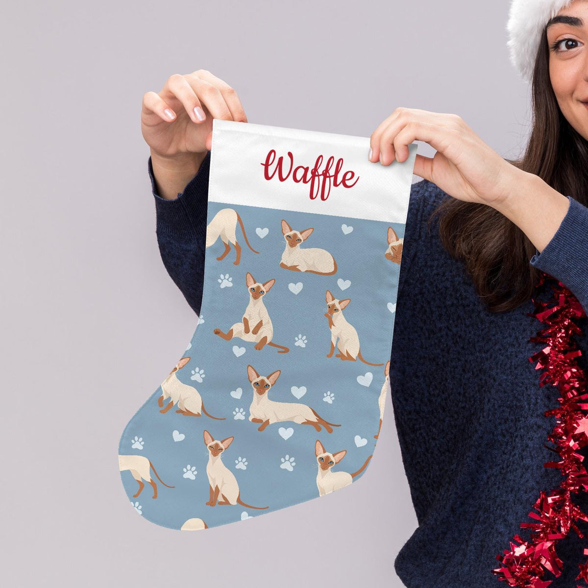 Colorpoint Shorthair Christmas stocking on dusty blue background with example name Waffle in red script on the white cuff; view 5.