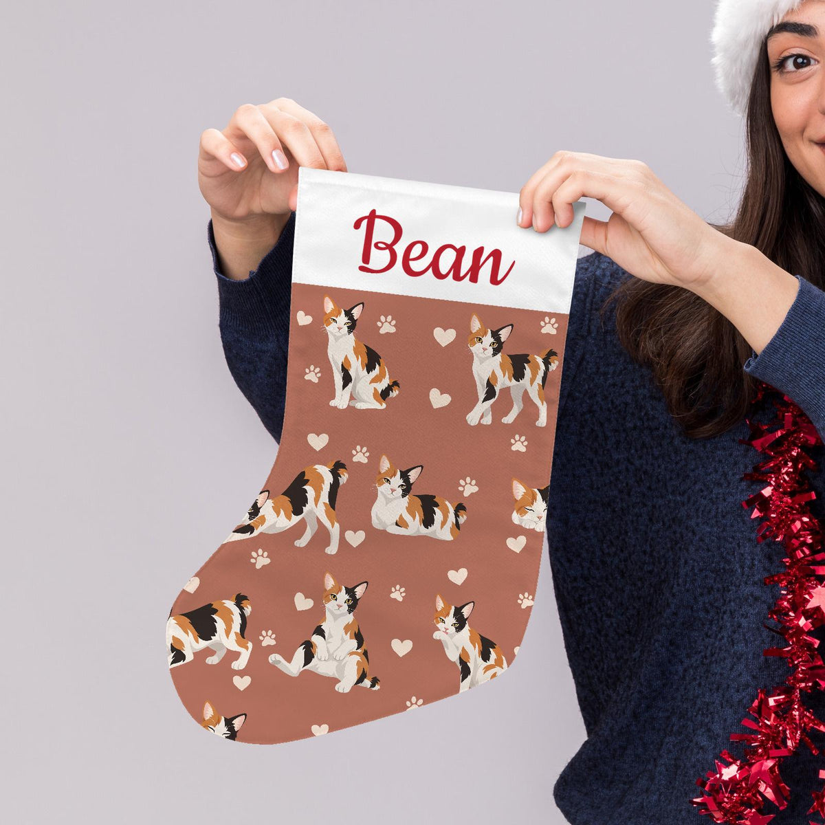 Japanese Bobtail Christmas stocking on muted terracotta background with example name Bean in red script on the white cuff; view 5.