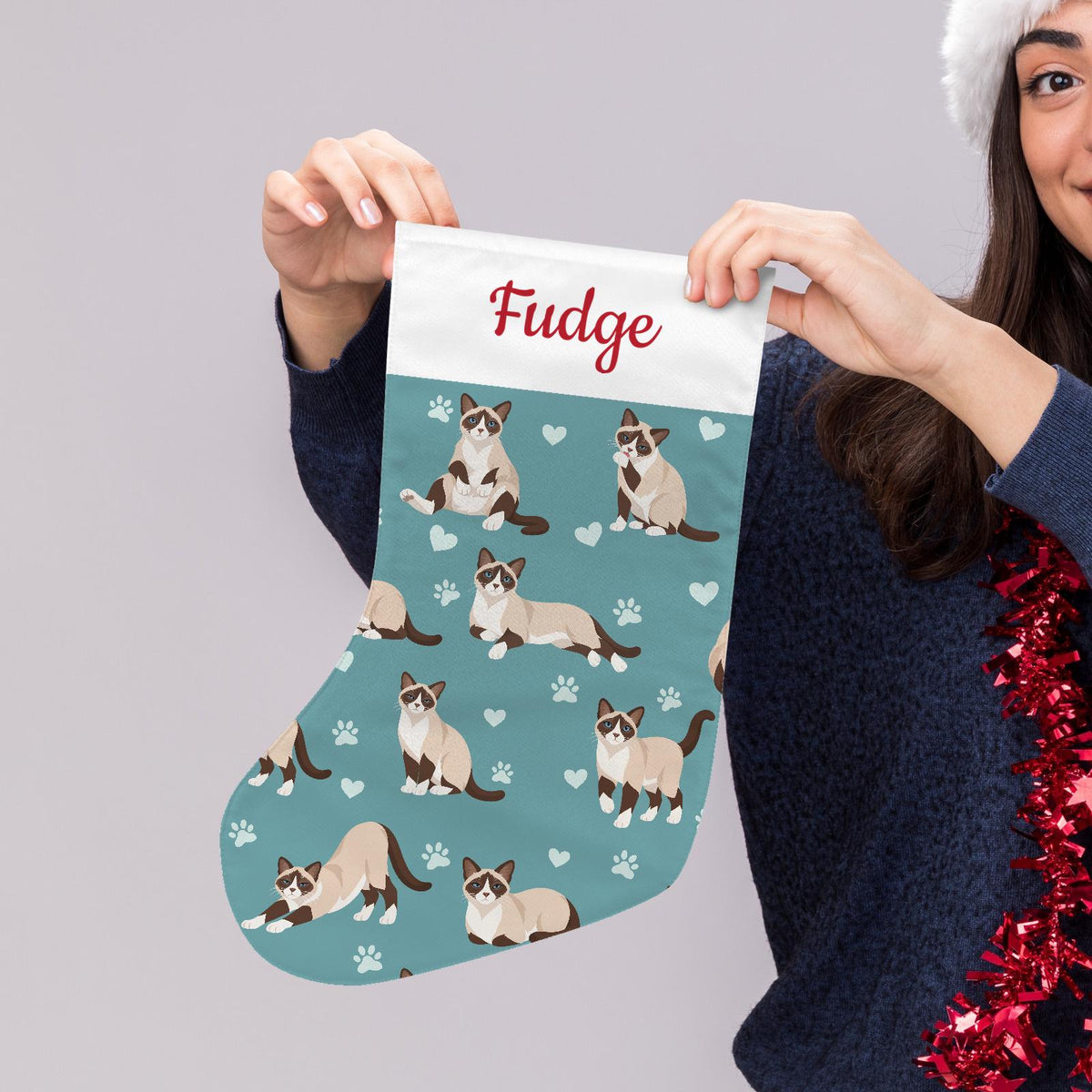 Snowshoe Christmas stocking on muted teal background with example name Fudge in red script on the white cuff; view 5.
