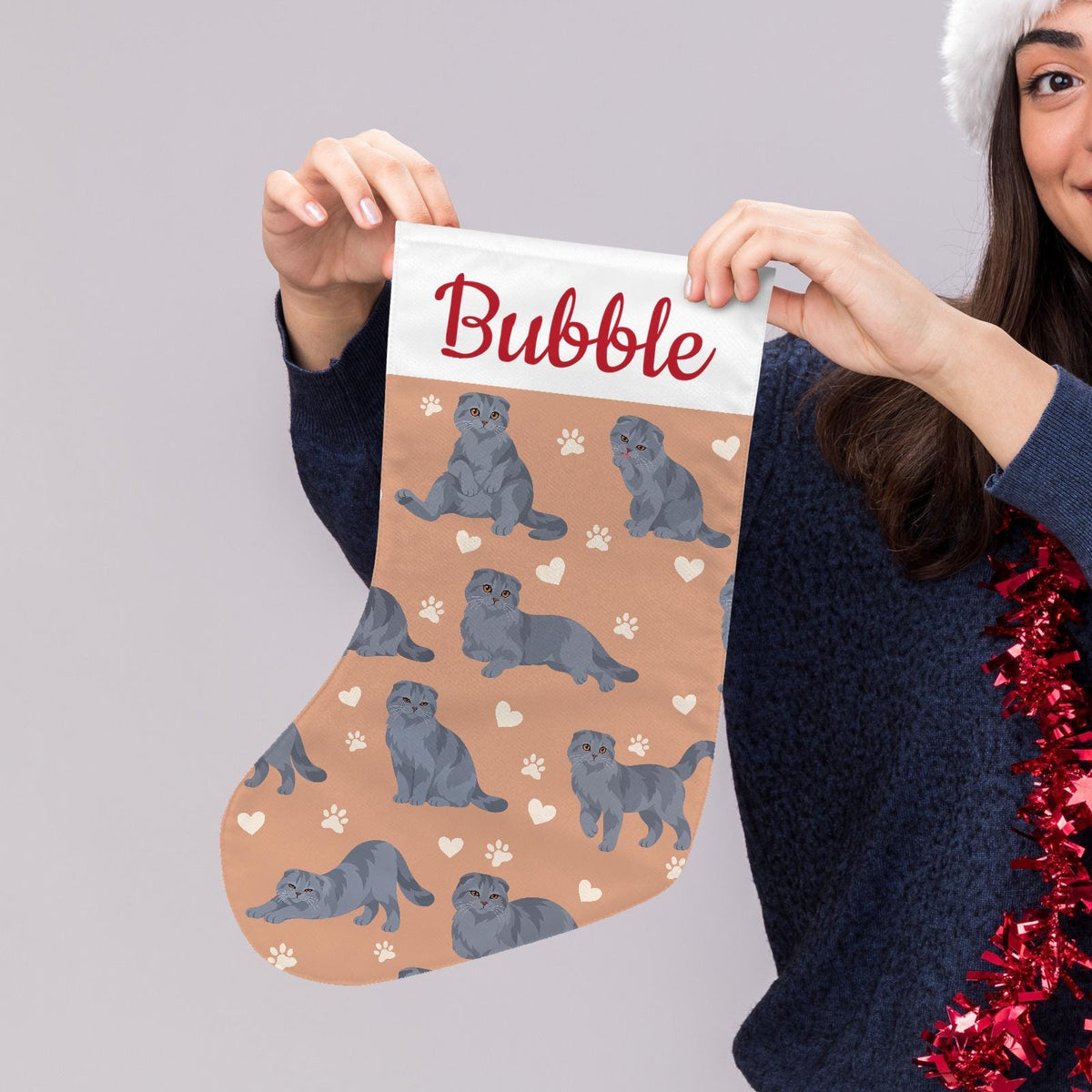 Scottish Fold Solid blue gray Christmas stocking on peach background with example name Bubble in red script on the white cuff; view 5.