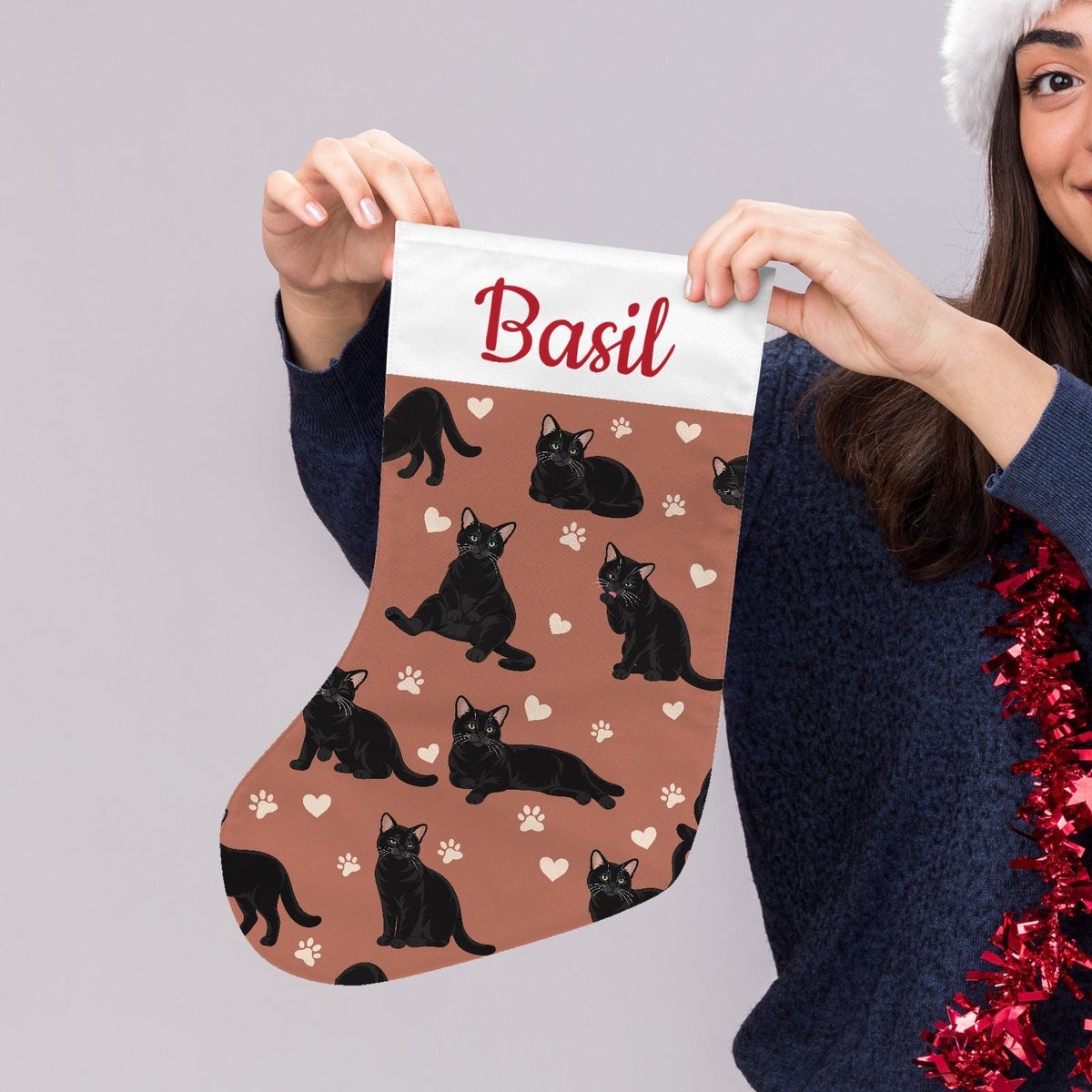 Domestic Shorthair Black Christmas stocking on muted terracotta background with example name Basil in red script on the white cuff; view 5.