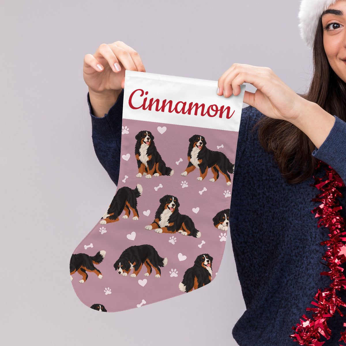 Bernese Mountain Dog Christmas stocking on dusty rose background with example name Cinnamon in red script on the white cuff; view 4.