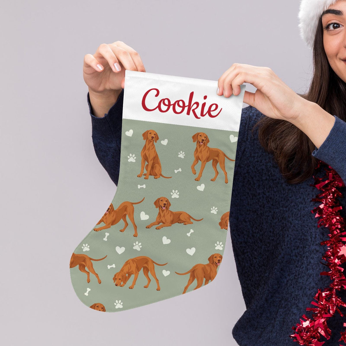 Vizsla Christmas stocking on soft sage background with example name Cookie in red script on the white cuff; view 5.