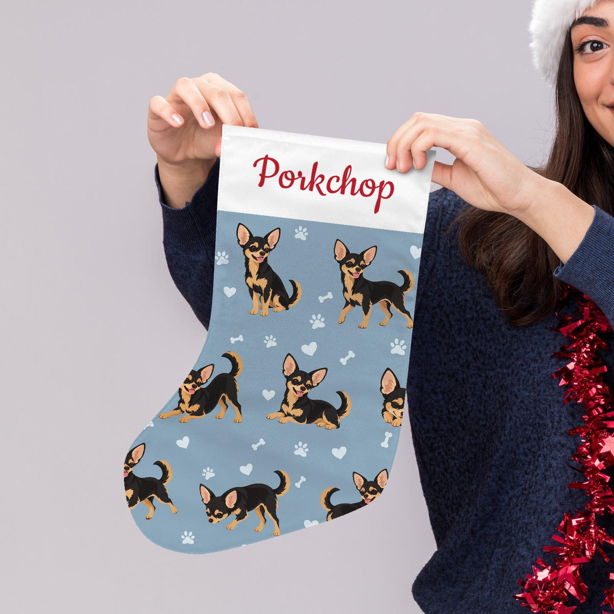 Chihuahua Black and Tan Christmas stocking on dusty blue background with example name Porkchop in red script on the white cuff; view 5.