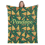 A woman is holding up a green blanket with a repeating pattern of pizza slices and various toppings, including pepperoni, mushrooms, and olives.