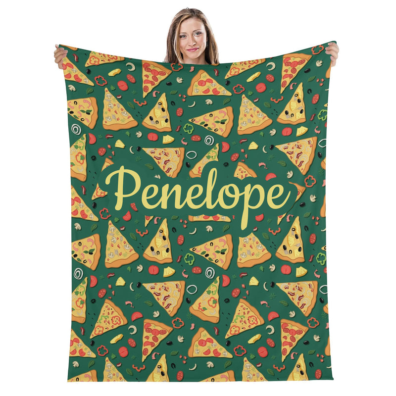 A woman is holding up a green blanket with a repeating pattern of pizza slices and various toppings, including pepperoni, mushrooms, and olives.