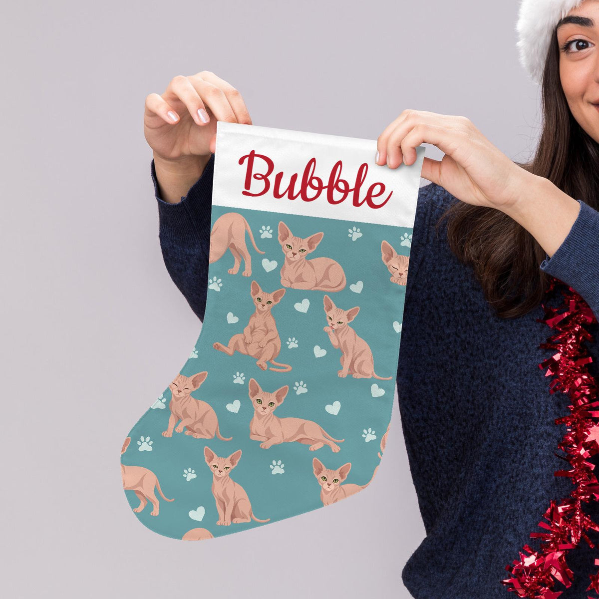 Sphynx Christmas stocking on muted teal background with example name Bubble in red script on the white cuff; view 5.