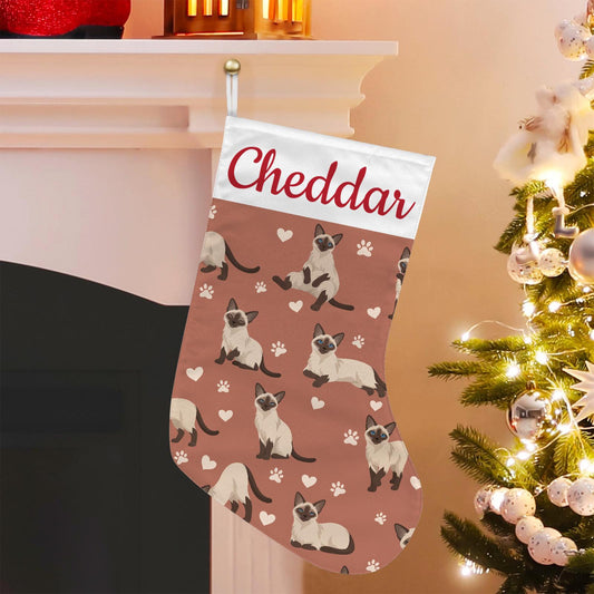 Siamese Christmas stocking on muted terracotta background with example name Cheddar in red script on the white cuff; view 1.