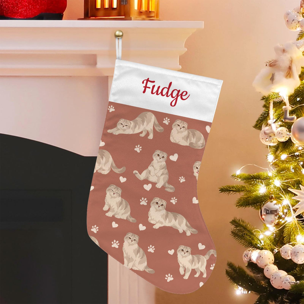Scottish Fold Christmas stocking on muted terracotta background with example name Fudge in red script on the white cuff; view 1.