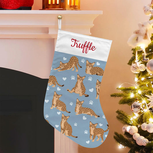 Ocicat Christmas stocking on dusty blue background with example name Truffle in red script on the white cuff; view 1.