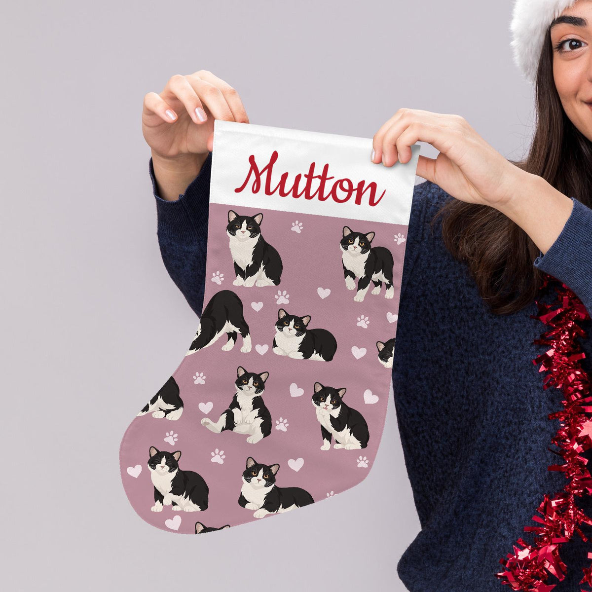 Manx Christmas stocking on dusty rose background with example name Mutton in red script on the white cuff; view 5.