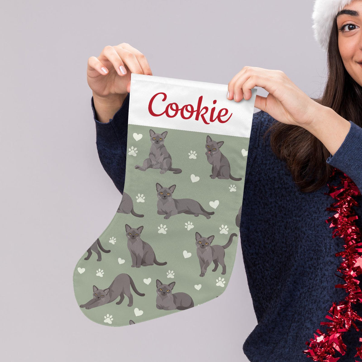 European Burmese Christmas stocking on soft sage background with example name Cookie in red script on the white cuff; view 5.