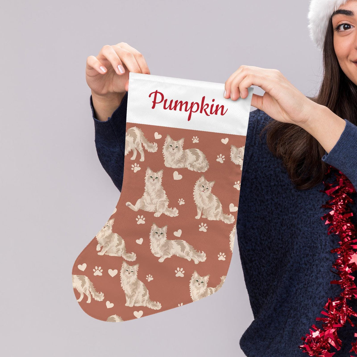 LaPerm Christmas stocking on muted terracotta background with example name Pumpkin in red script on the white cuff; view 5.