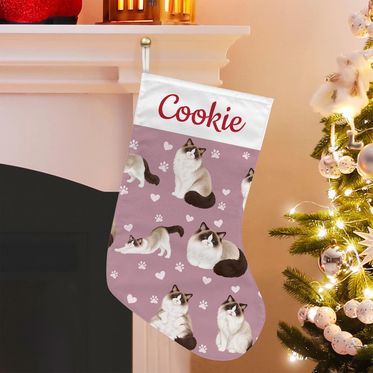 Ragdoll Seal bicolor Christmas stocking on dusty rose background with example name Cookie in red script on the white cuff; view 1.