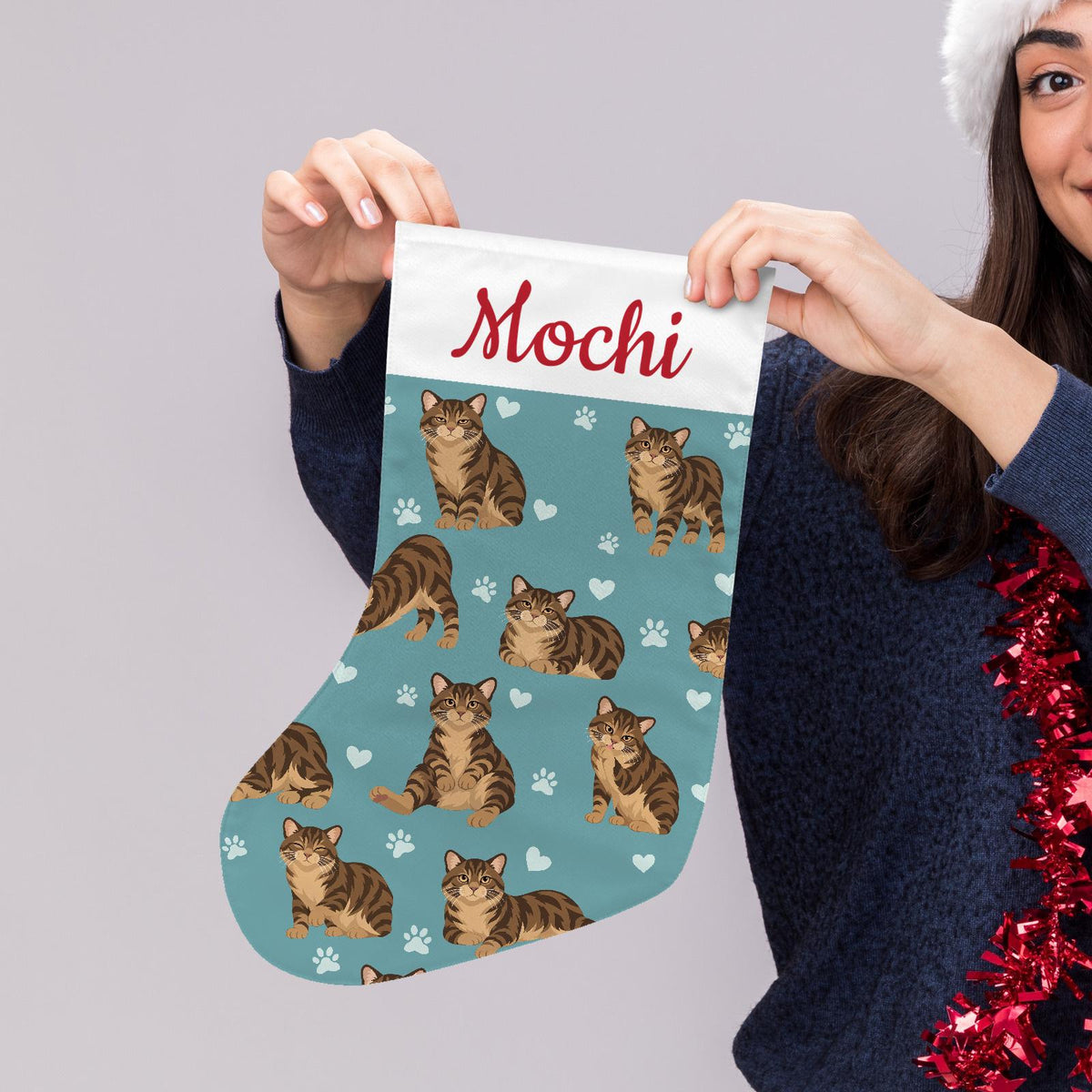 Manx Brown tabby Christmas stocking on muted teal background with example name Mochi in red script on the white cuff; view 5.