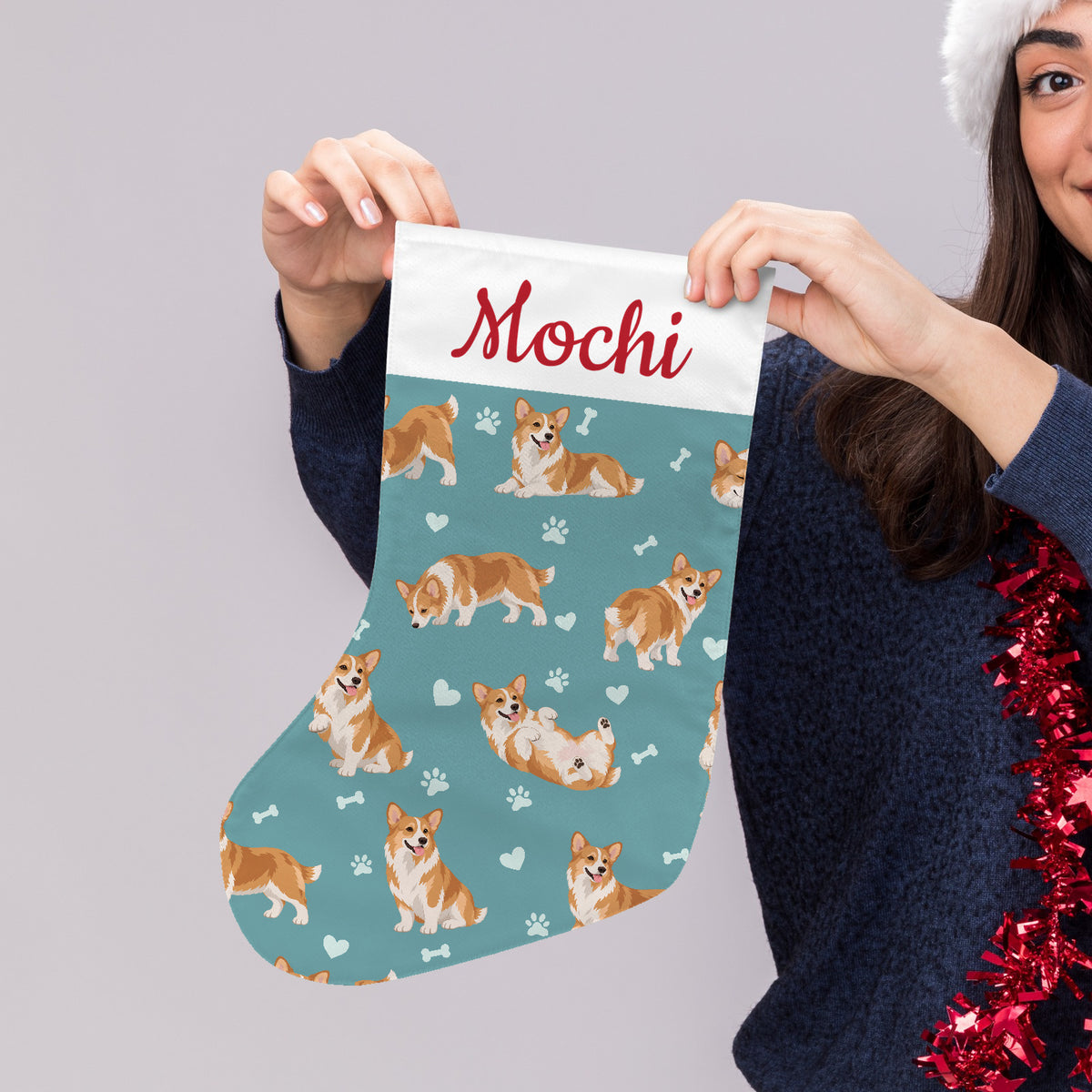 Pembroke Welsh Corgi Christmas stocking on muted teal background with example name Mochi in red script on the white cuff; view 4.