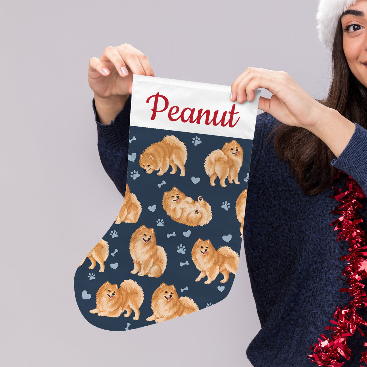 Pomeranian Christmas stocking on deep navy background with example name Peanut in red script on the white cuff; view 4.