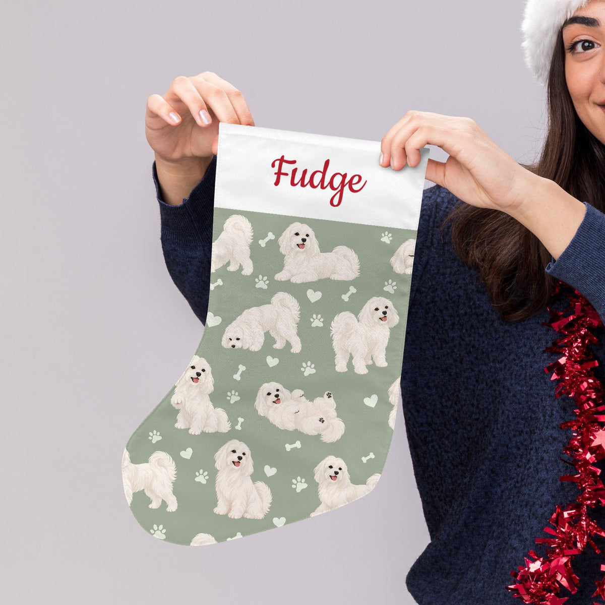 Maltese Christmas stocking on soft sage background with example name Fudge in red script on the white cuff; view 5.
