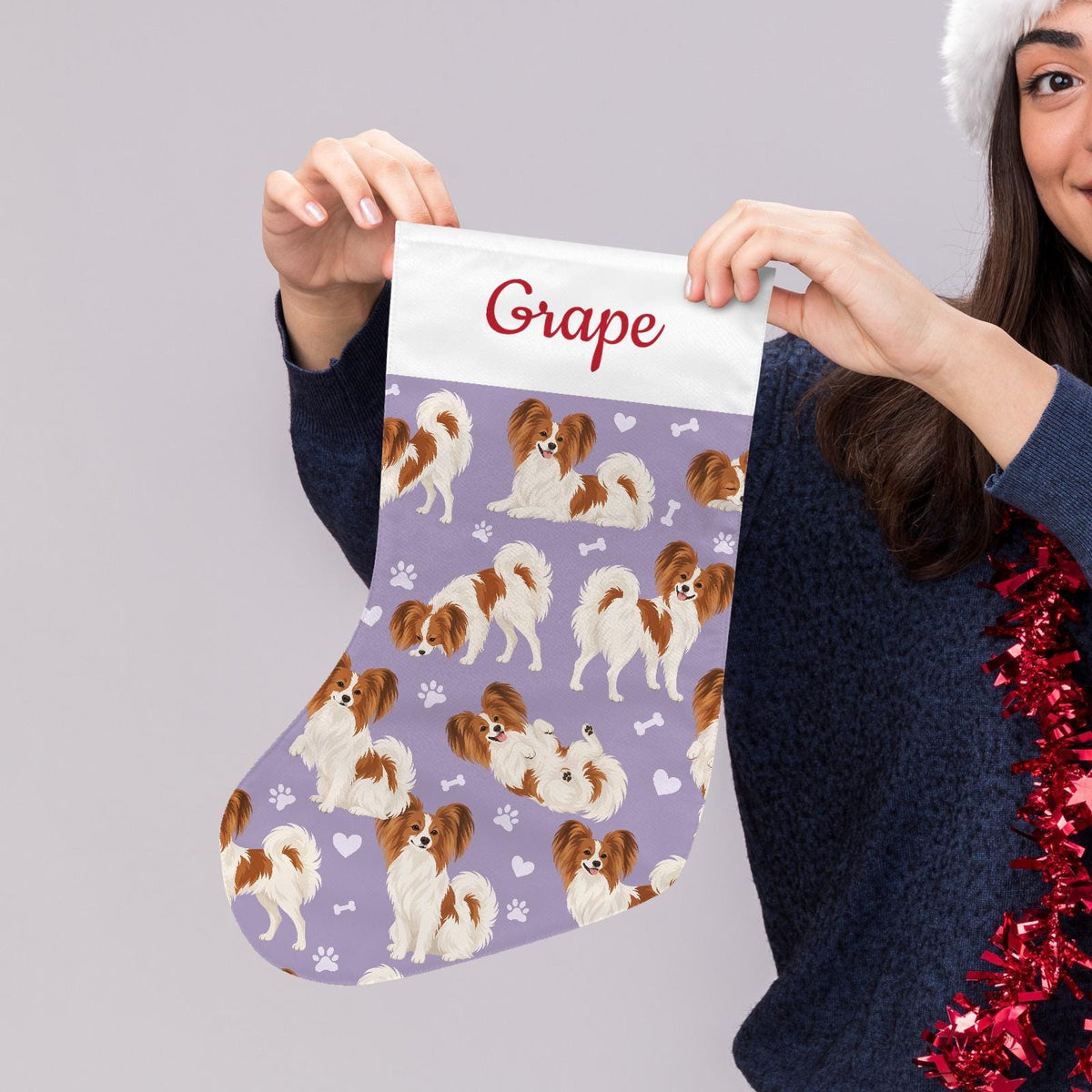 Papillon Christmas stocking on soft lavender background with example name Grape in red script on the white cuff; view 5.