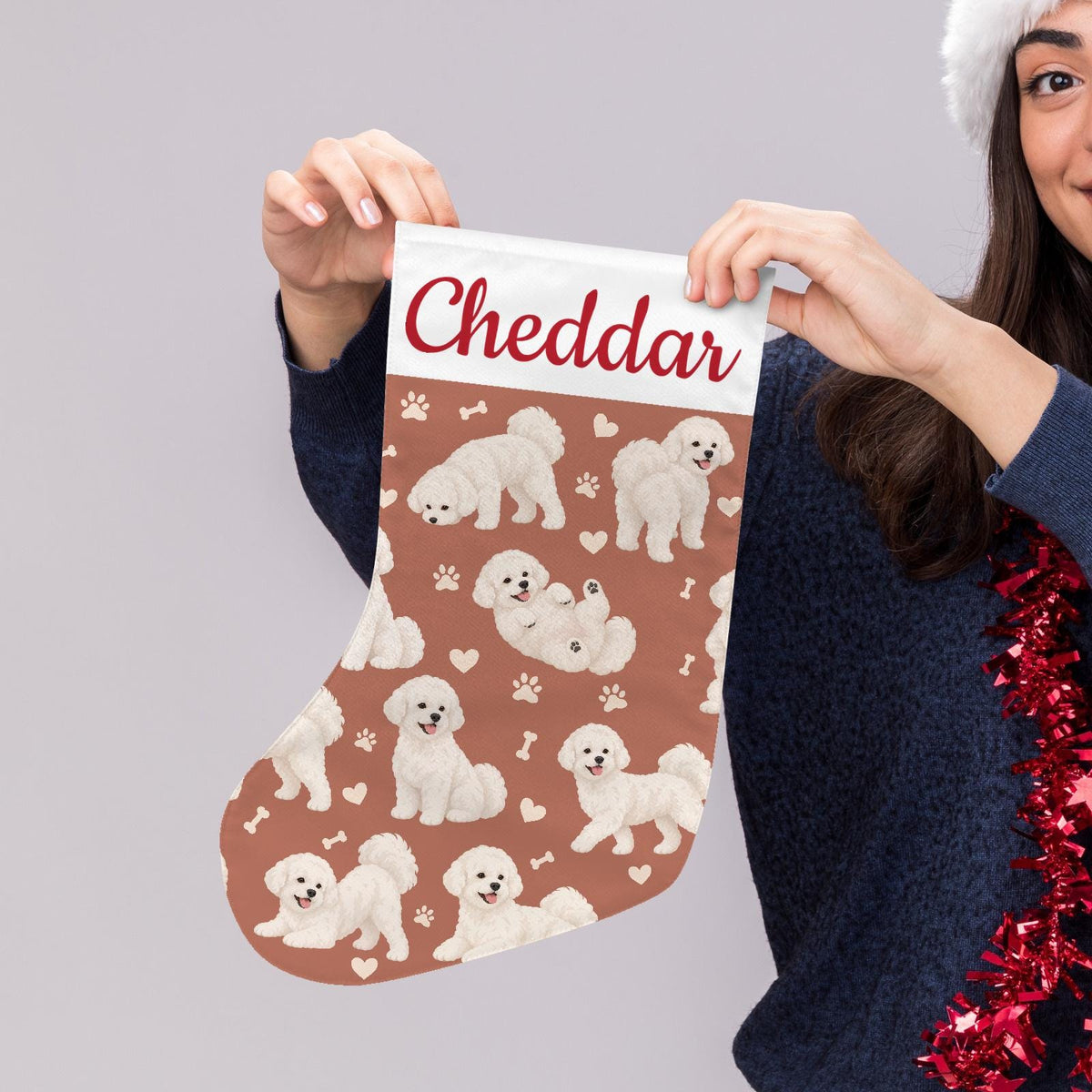 Bichon Frise Christmas stocking on muted terracotta background with example name Cheddar in red script on the white cuff; view 5.