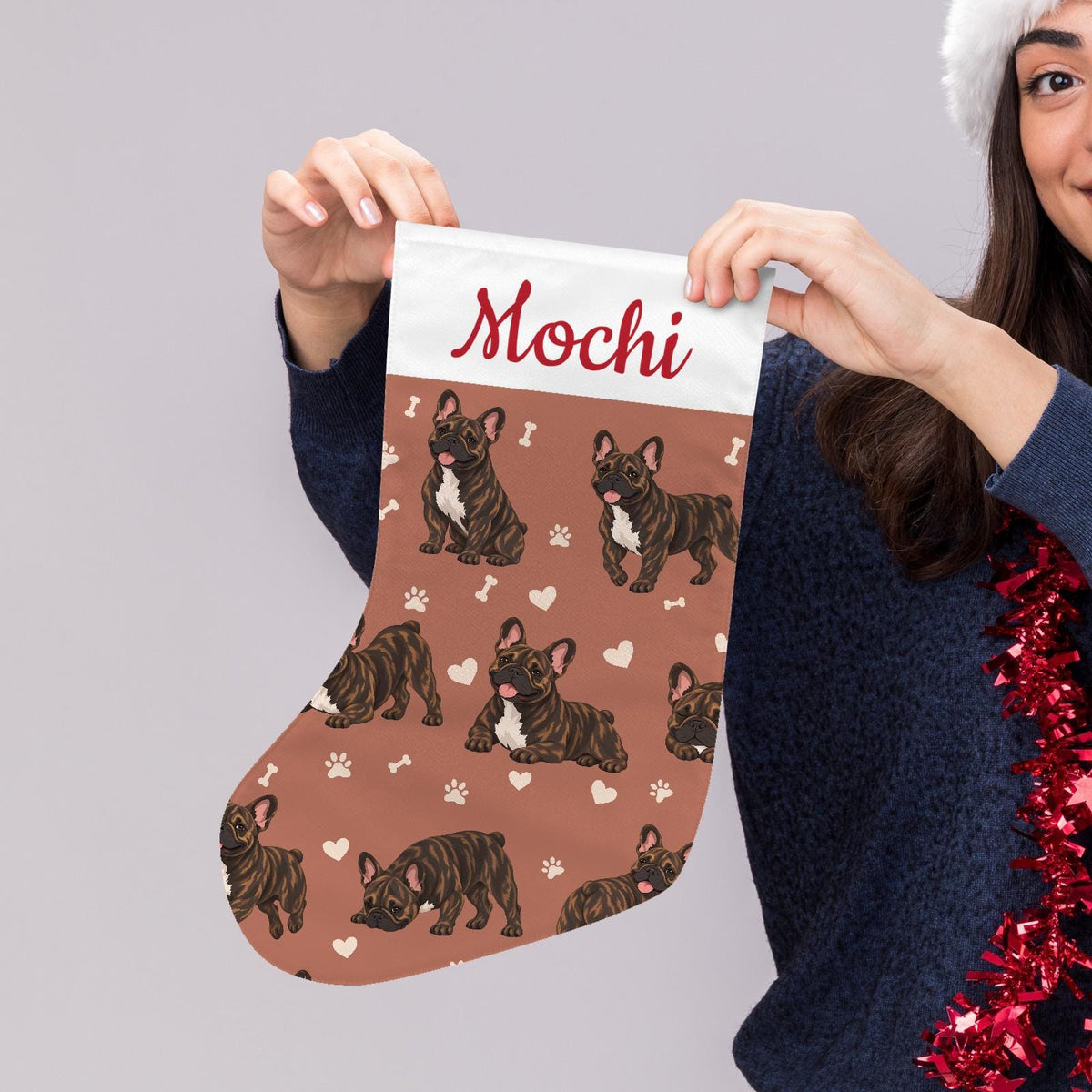 French Bulldog Brindle Christmas stocking on muted terracotta background with example name Mochi in red script on the white cuff; view 5.