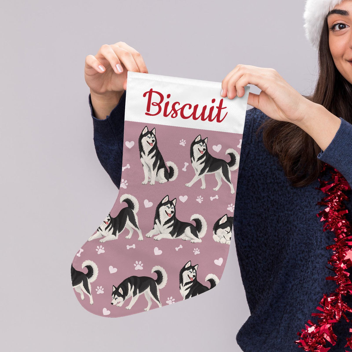 Siberian Husky Black and White Christmas stocking on dusty rose background with example name Biscuit in red script on the white cuff; view 5.