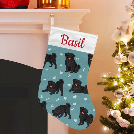Pug Black Christmas stocking on muted teal background with example name Basil in red script on the white cuff; view 1.