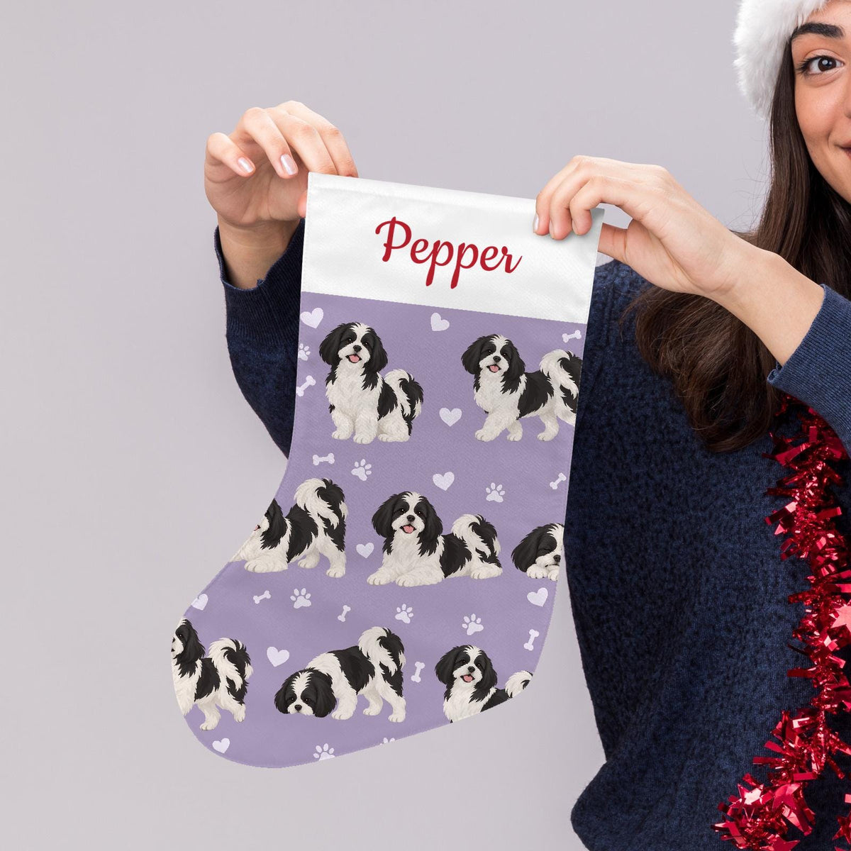Shih Tzu Black and White Christmas stocking on soft lavender background with example name Pepper in red script on the white cuff; view 5.