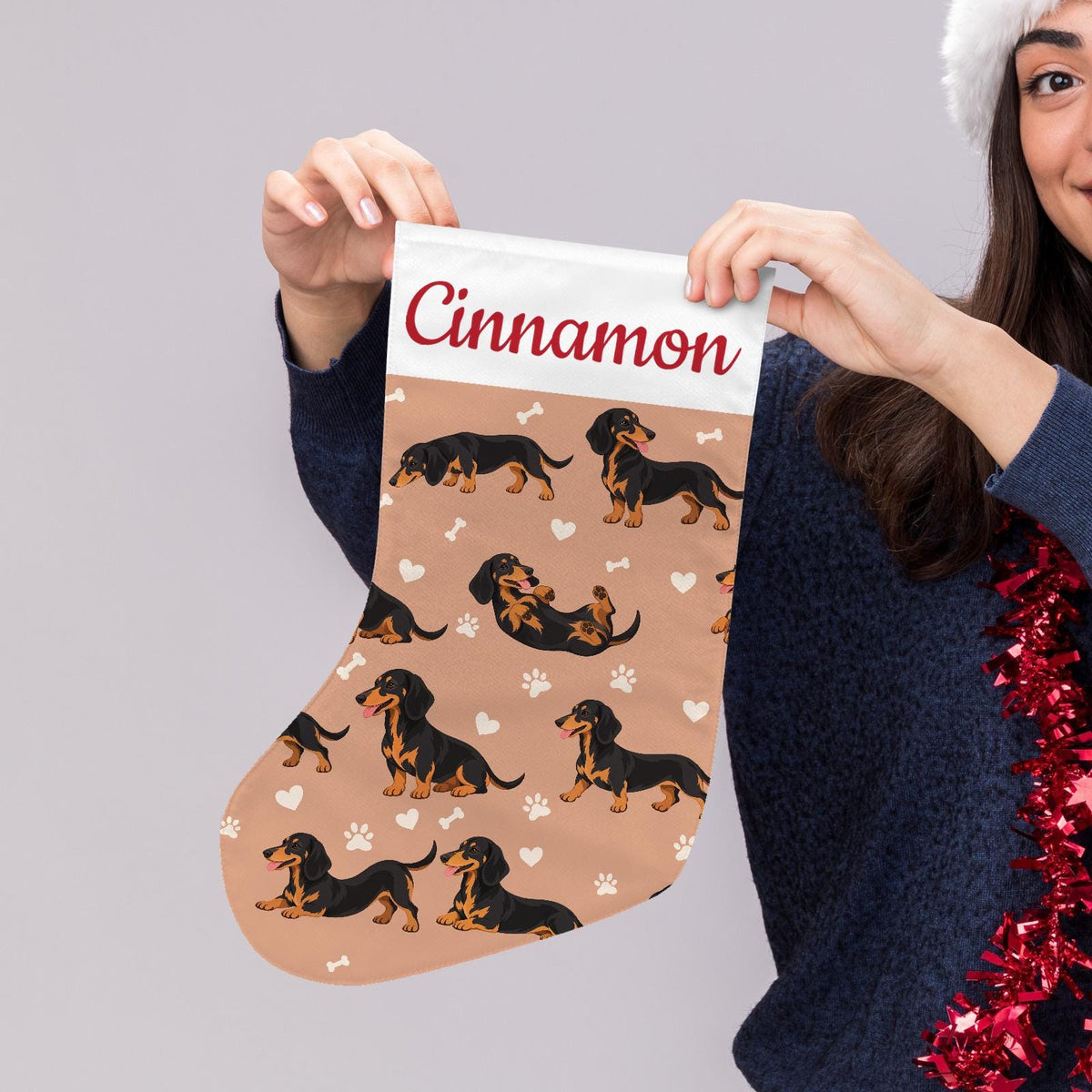 Dachshund Black and Tan Christmas stocking on peach background with example name Cinnamon in red script on the white cuff; view 5.